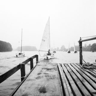 Boat docked on wet wooden pier near water.