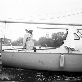 Person sailing small boat in rainy weather.
