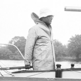 Person sailing small boat in rainy weather.
