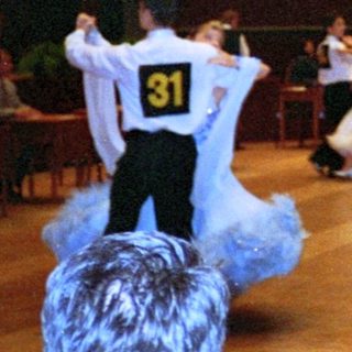 Ballroom dance competition with numbered participants.