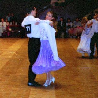 Ballroom dance competition with numbered participants.