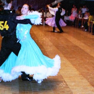 Ballroom dance competition with performers on wooden floor.