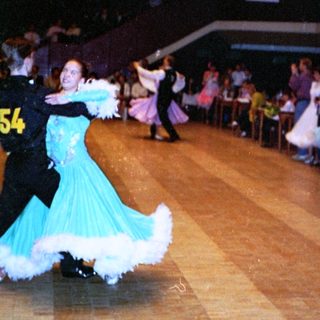 Ballroom dance competition with performers on wooden floor.