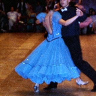 Ballroom dancers performing in a well-lit hall.