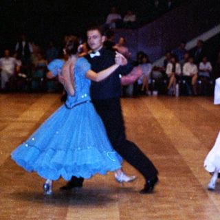 Ballroom dancers performing in a well-lit hall.