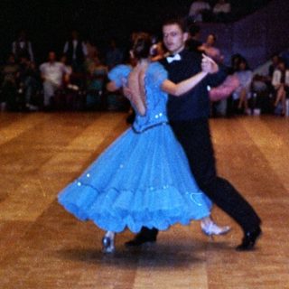 Ballroom dancers performing in a well-lit hall.