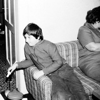 Two children playing video game with adult nearby.