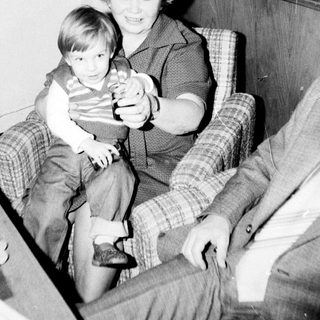 Woman holding young child indoors with toy.
