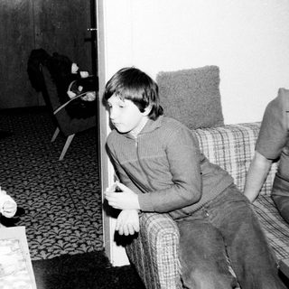 Two children sitting indoors, watching television.