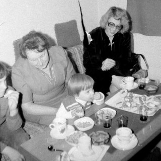 Family gathering enjoying tea and desserts indoors.