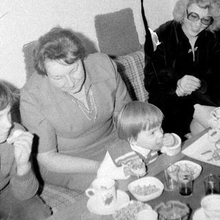Family gathering enjoying tea and desserts indoors.