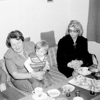 Family gathering indoors with tea and snacks.
