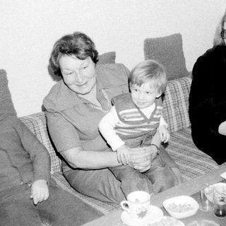 Family gathering indoors with tea and snacks.