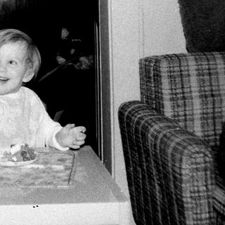 Child blowing out birthday candles indoors.