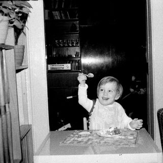 Child blowing out birthday candles indoors.