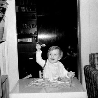 Child blowing out birthday candles indoors.