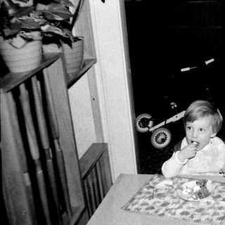 Two children eating cake indoors, one seated at table.
