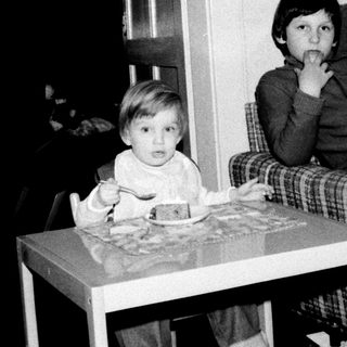 Two children sitting indoors at a small table.