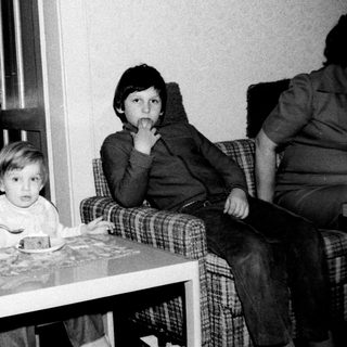 Two children sitting indoors at a small table.