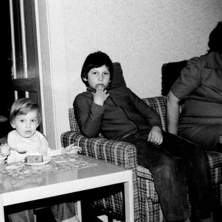 Two children sitting indoors at a small table.