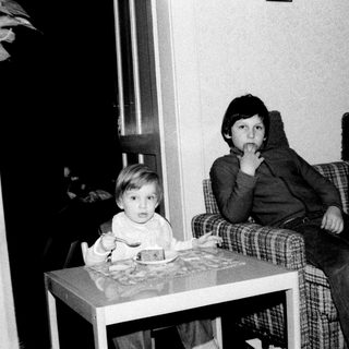 Two children sitting indoors at a small table.