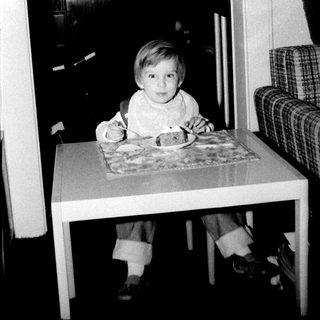 Young child sitting at table with food.