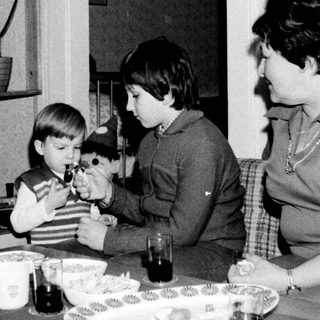 Family gathering around table with children playing with toy.