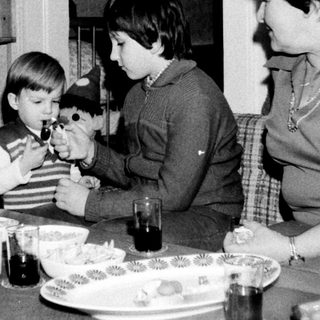 Family gathering around table with children playing with toy.