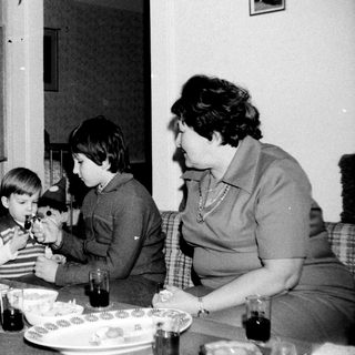 Family gathering around table with children playing with toy.