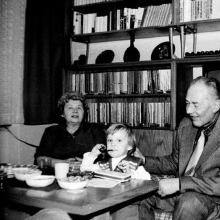 Family sharing a meal indoors during the 1960s-70s.