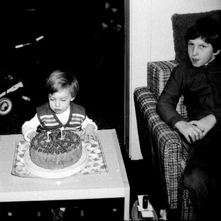 Young boy blowing out birthday cake candle indoors.