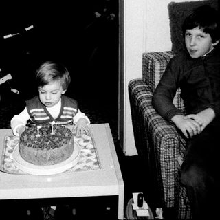 Young boy blowing out birthday cake candle indoors.