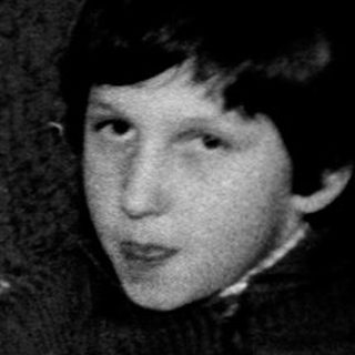 Young boy blowing out birthday cake candle indoors.