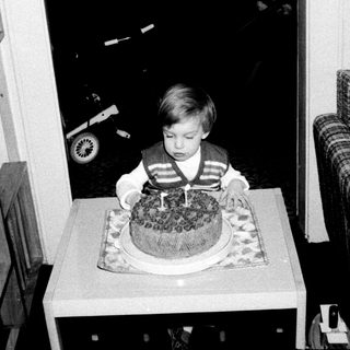 Young boy blowing out birthday cake candle indoors.