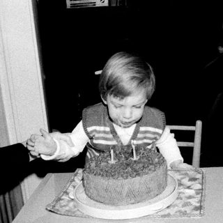 Young child blowing out birthday cake candles indoors.