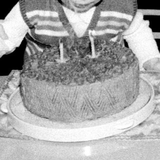 Young child blowing out birthday cake candles indoors.