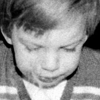 Young child blowing out birthday cake candles indoors.