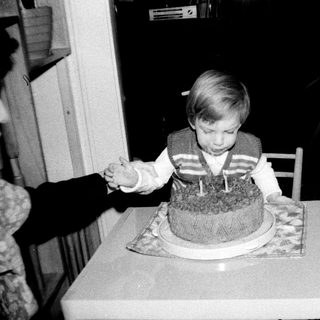 Young child blowing out birthday cake candles indoors.