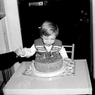 Young child blowing out birthday cake candles indoors.