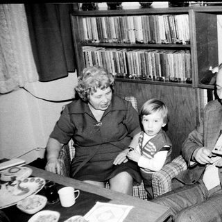 Family trio enjoying indoor gathering with television.