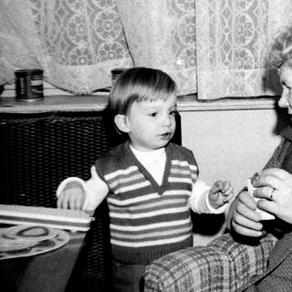 A woman teaching a young boy to play a small musical instrument.