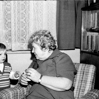 A woman teaching a young boy to play a small musical instrument.