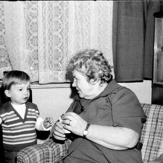 A woman teaching a young boy to play a small musical instrument.