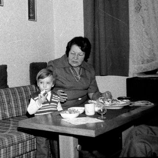 Family sharing meal indoors during the 1970s-80s.