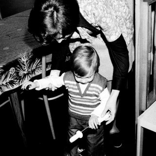 A woman helping a young child brush teeth.