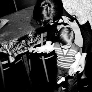A woman helping a young child brush teeth.