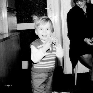 A young boy smiling indoors with a woman.