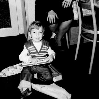 A woman and young boy indoors, smiling together.