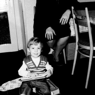 A woman and young boy indoors, smiling together.