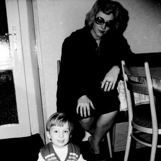 A woman and young boy indoors, smiling together.